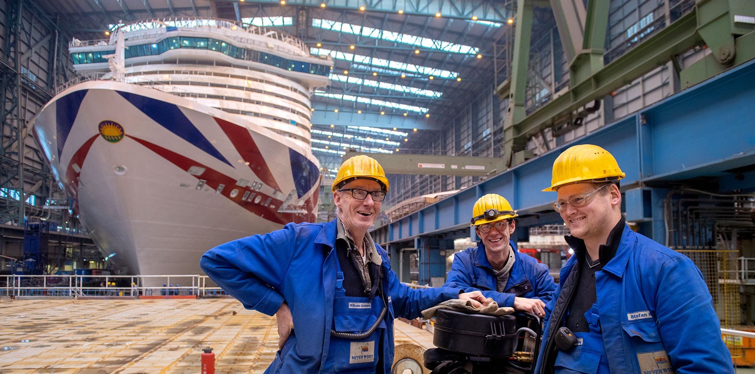 Arbeiter der Meyer Werft vor der Iona, einem LNG-getriebenen Kreuzfahrtschiff für 5200 Passagiere