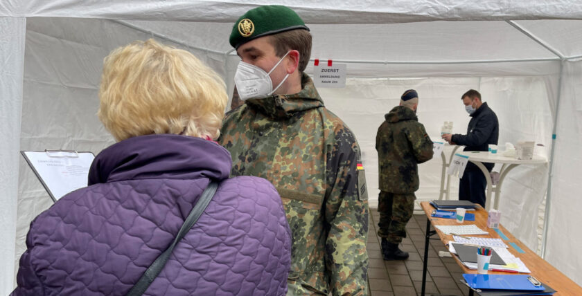 A soldier from the Bremen Homeland Security Company helps a Bremen citizen fill out the registration form. Photo: Bundeswehr / Krey"
