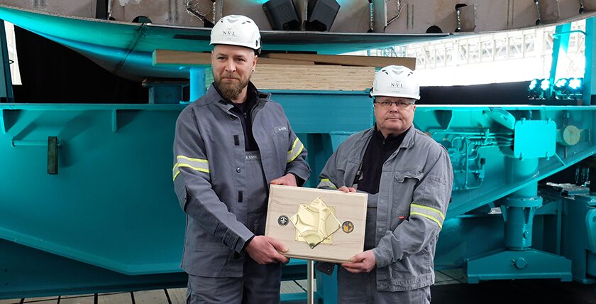Werftmitarbeiter Andre Loth und Heiko Schulz mit der Gedenkmünze. Foto: hsc
